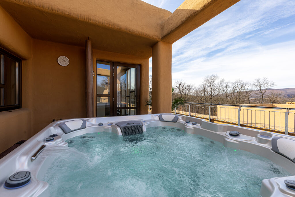 A hot tub with pristine water quality sits under a covered patio with no one in it.