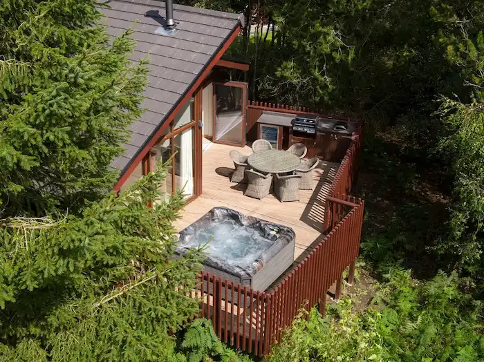 13 Hot Tub Deck Ideas For Inspiration 1 Picture of a Wellis hot tub on an elevated wooden balcony.
