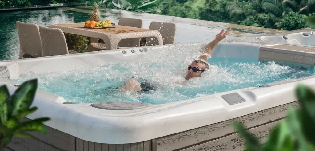 Swim Spa Backyard Ideas 1 Person swimming in a Wellis swim spa for the blog about swim spa backyard ideas.