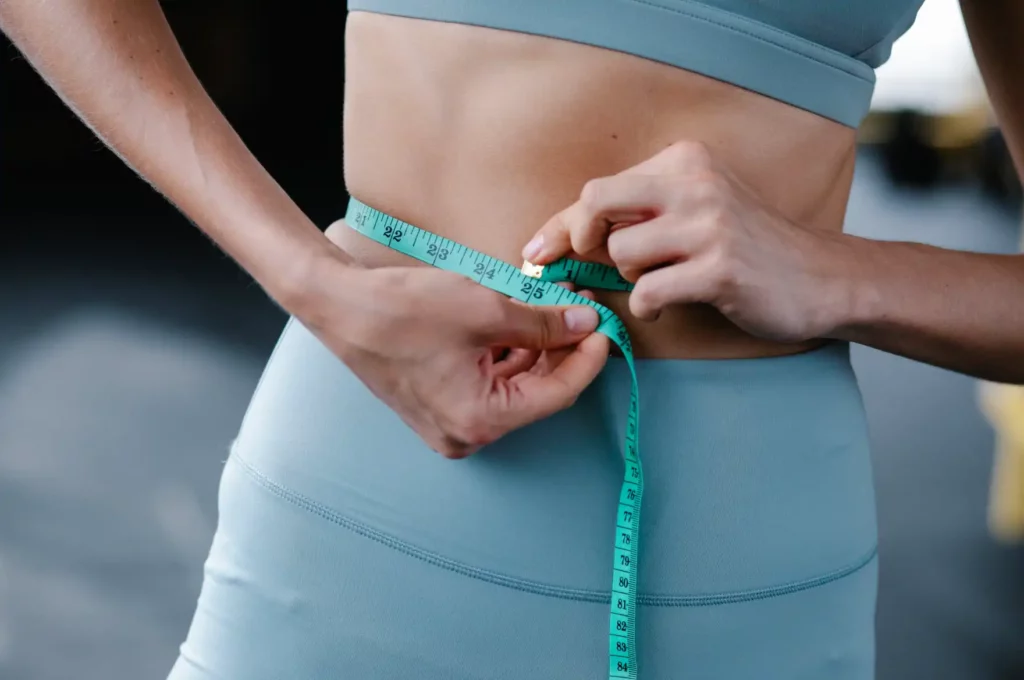 a woman measuring her waist wondering how to lose water weight fast