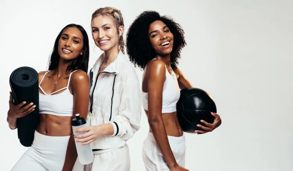 Three women with fitness equipment for the blog about how to workout at home.