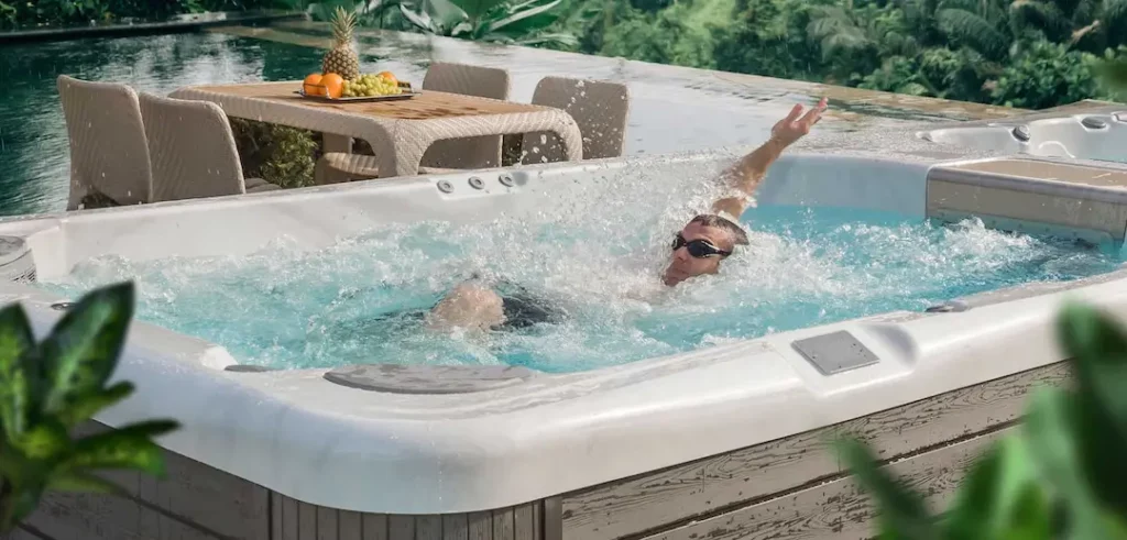 Person swimming in a Wellis swim spa for the blog about swim spa backyard ideas.